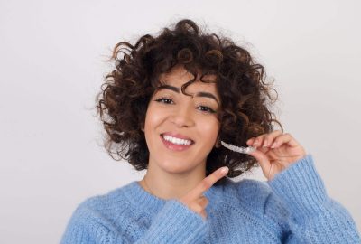 Young,Beautiful,Arab,Woman,Holding,An,Invisible,Aligner,Braces,Against